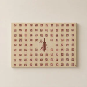 Beige wall art featuring a grid of small red geometric squares and a central Arabic calligraphic inscription.