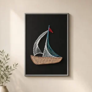 Framed string-art sailboat on a black background, with white sail, blue rigging, and a woven brown hull.