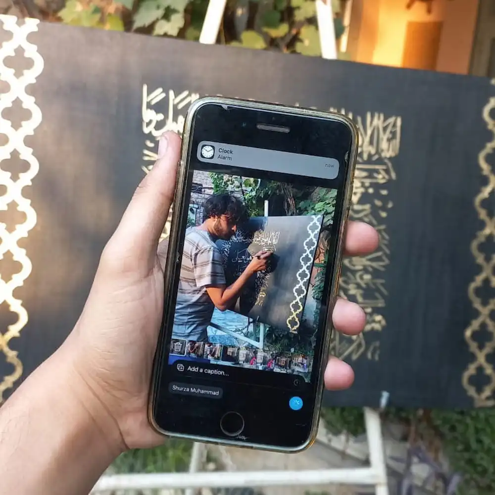 calligraphy - Artoza Crafts | Where Craft Becomes Style Person holding a smartphone to capture a chalkboard drawing with a white decorative border.