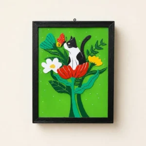 Framed green papercraft art of a black-and-white cat perched on a red flower with a butterfly nearby.