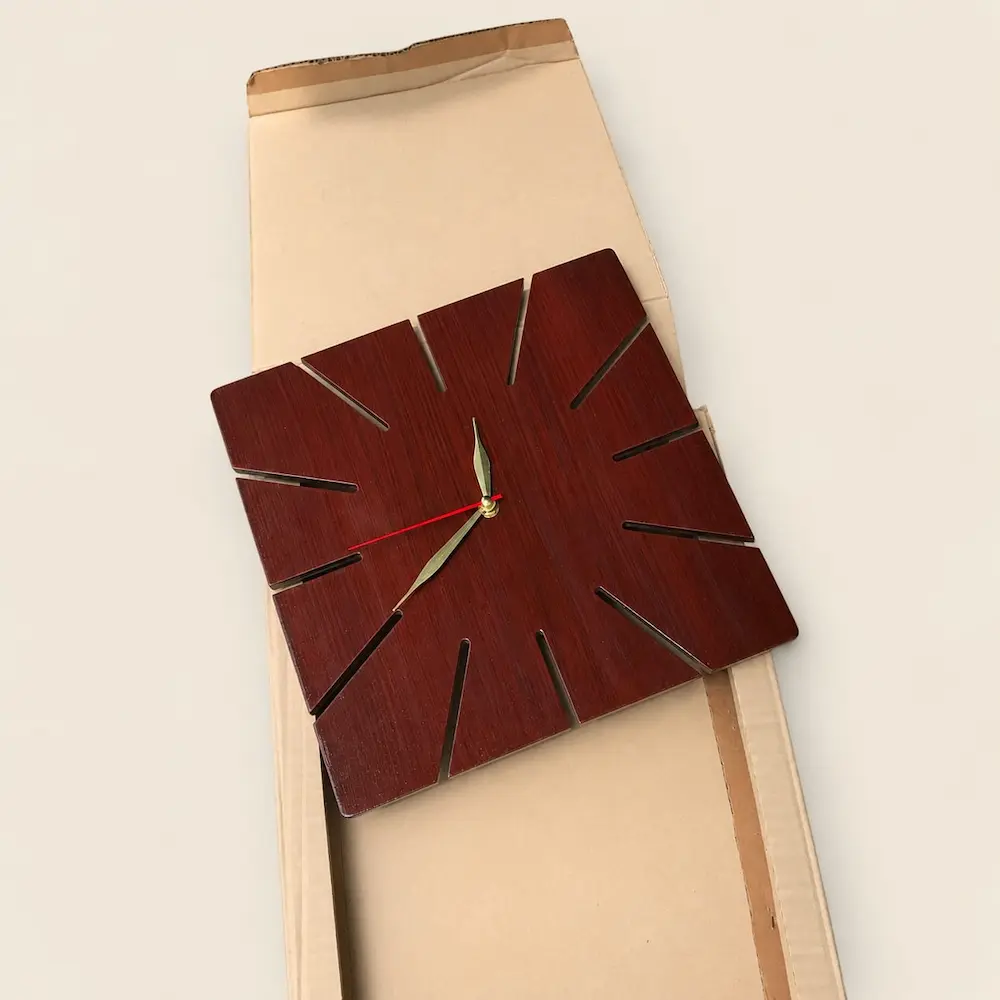 clock packing - Artoza Crafts | Where Craft Becomes Style Decorative square wooden wall clock with diagonal cut slots mounted on a cardboard box backdrop.