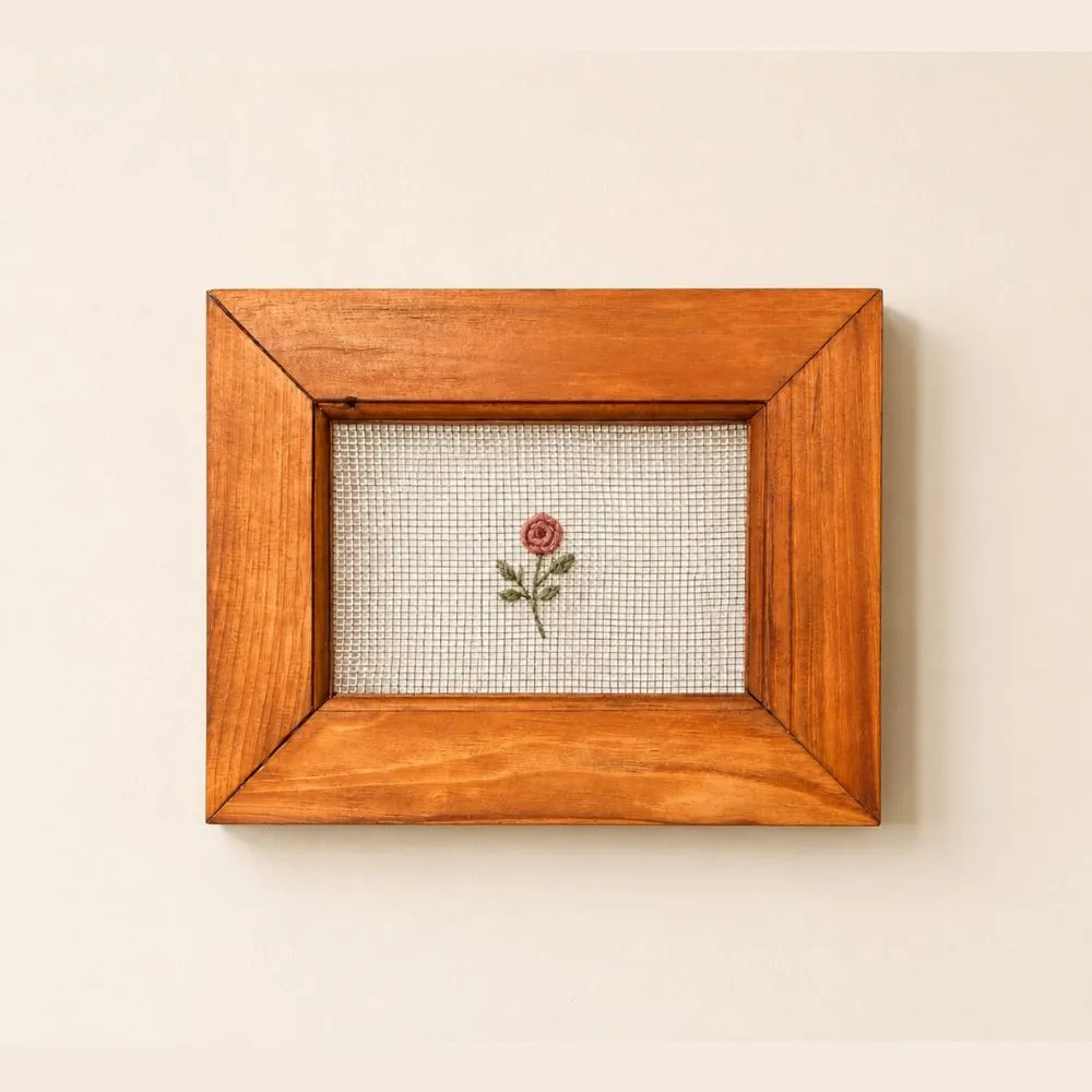 cross stitch frame - Artoza Crafts | Where Craft Becomes Style Small pink rose embroidery framed in a warm wooden frame on a light wall.