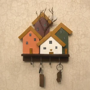 Decorative wooden key rack shaped like colorful houses with four hooks for keys on a beige wall.