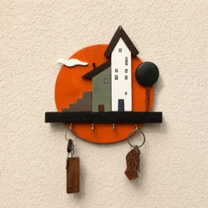 Decorative wall-mounted key rack featuring two house shapes on an orange circular backdrop with several hooks and hanging keys.