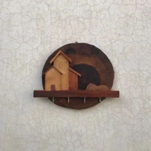 Decorative wall hook rack with a round burnt-wood plaque and small wooden houses on a shelf with four metal hooks beneath.