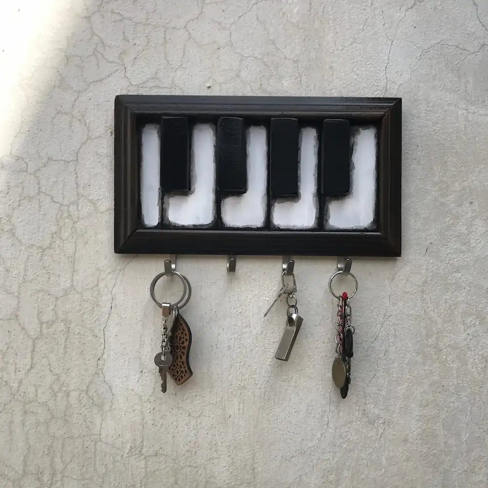 piano keyholder - Artoza Crafts | Where Craft Becomes Style Framed key holder formed from piano keys spelling LOVE, with several keychains hanging from hooks.