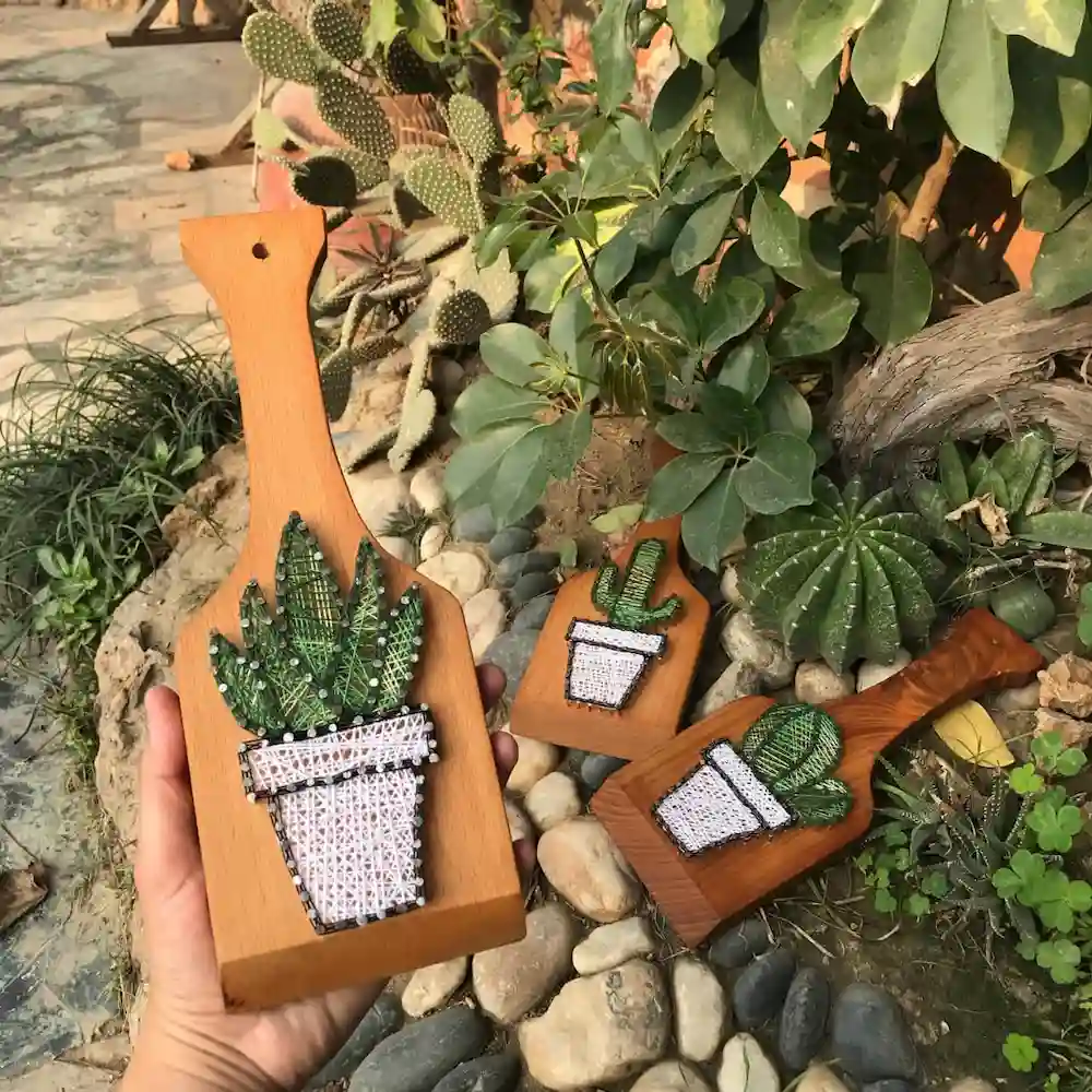 string art ideas - Artoza Crafts | Where Craft Becomes Style Wooden paddle with a beaded cactus in a pot, held outdoors among stones and greenery.