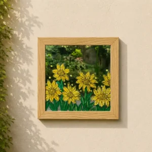 Framed painting of bright yellow flowers on green foliage, hung on a light beige wall with ivy to the left.