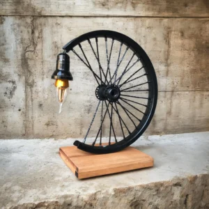 Half of a black bicycle wheel with spokes and hub mounted on a wooden block against a textured concrete wall, with a hanging lamp attached to the wheel hub area.