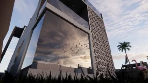 contemporary-villa-saudi-arabia1 - Artoza Crafts | Where Craft Becomes Style Angled view of a modern glass building with a perforated metal screen, reflecting the cloudy sunset sky beside a palm tree and a pink flamingo statue in the yard.