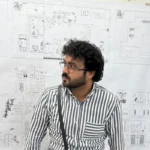 contemporary-villa-saudi-arabia8 - Artoza Crafts | Where Craft Becomes Style Portrait of a man with glasses and beard wearing a striped shirt, standing in front of architectural drawings on a wall.