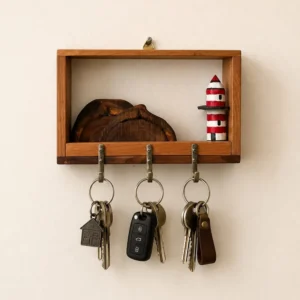 Wall-mounted wooden key rack with three metal hooks holding several keys and a small red-and-white lighthouse ornament beside a wood slice.