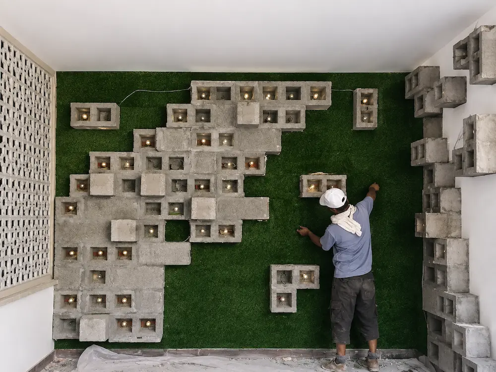 Installation of artificial green turf behind the sculptural concrete block feature wall to create a natural textured backdrop for the private dining room.