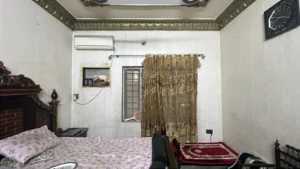 Traditional bedroom with ornate dark wood bed, floral bedding, and decorative ceiling trim in gold and dark tones.