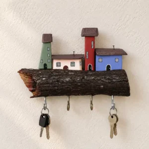 Wooden key holder shaped like a log with colorful miniature houses on top and two key rings hanging below it